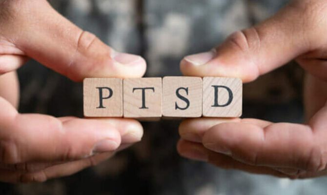 Close up of hands holding cubes with the letters PTSD spelled out.