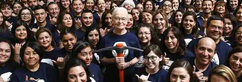Diana Natalicio holding a UTEP pick-axe, surrounded by students and staff wearing the same shirt