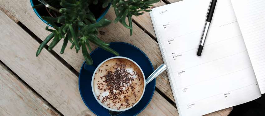 A blank appointment book next to a cup of coffee