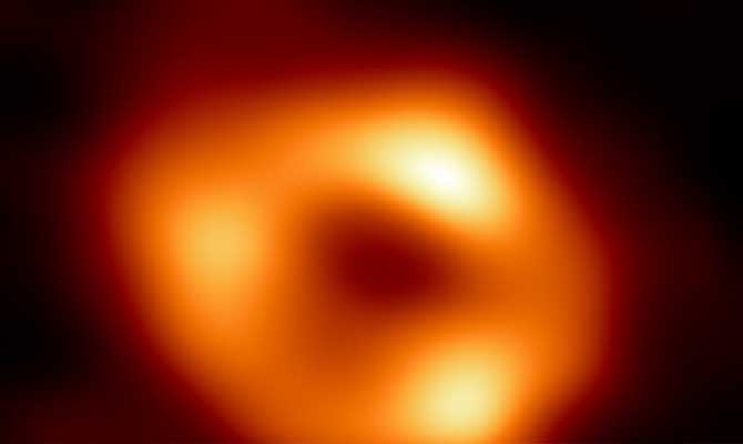 telescope image of a black hole, which has a near circle black center surrounded by an imperfect ring of lights