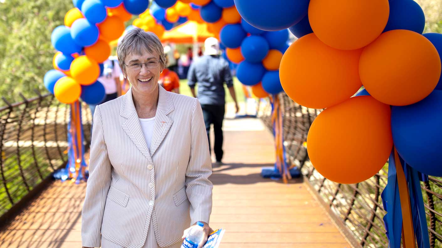 UT El Paso President Heather Wilson walking outside underneath rows of blue and orange baloons