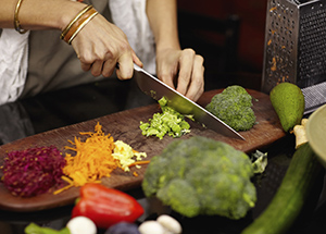 a pair of hands cutting vegitables and fruit on a cutting and serving board