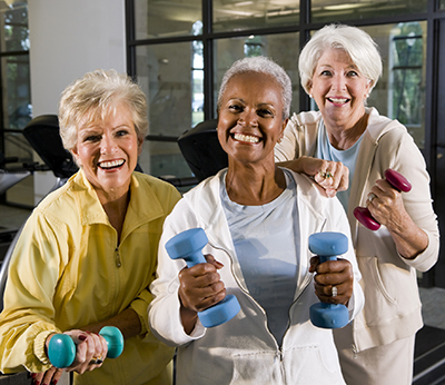 A group of women smiling and holding dumbells