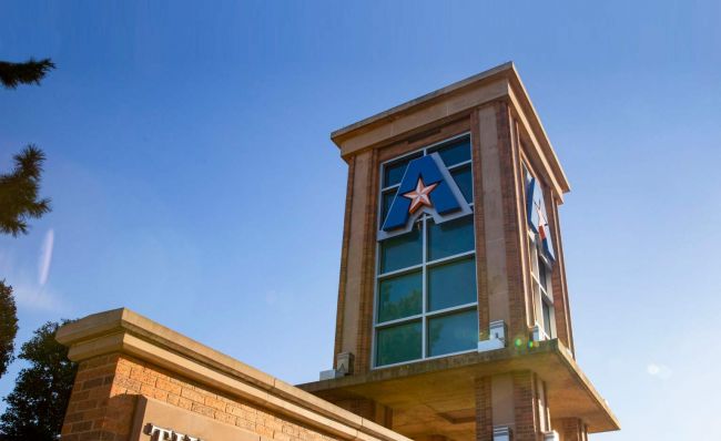 UT Arlington tower close up view of the top with the "A star" logo against a deep blue sky