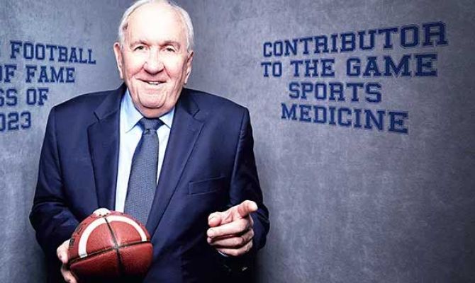 Dr. DeLee in a suit with a football in his hand.