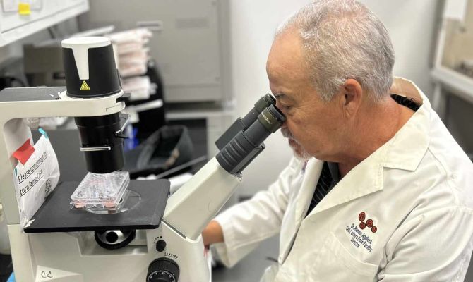 UTEP Researcher in a lab looking through a powerful microscope