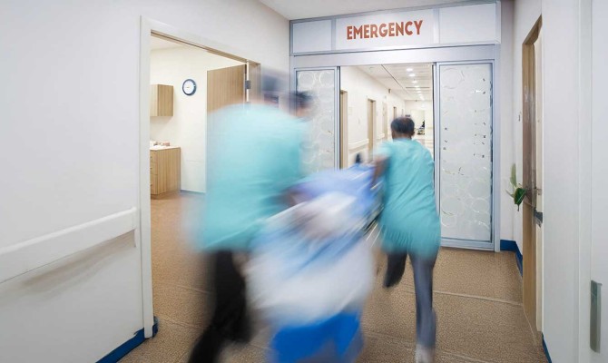 Emergency room scene with doctors rushing a patient through a door