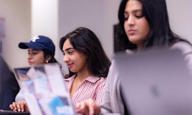 UT Dallas students working on laptops in a commons area