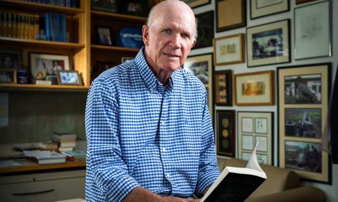 Steven McKnight, Ph.D. in his office holding a book open