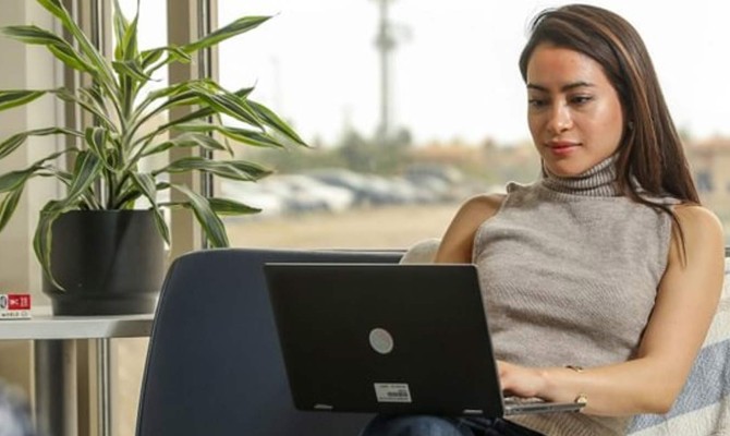A female student sitting down and reading a laptop