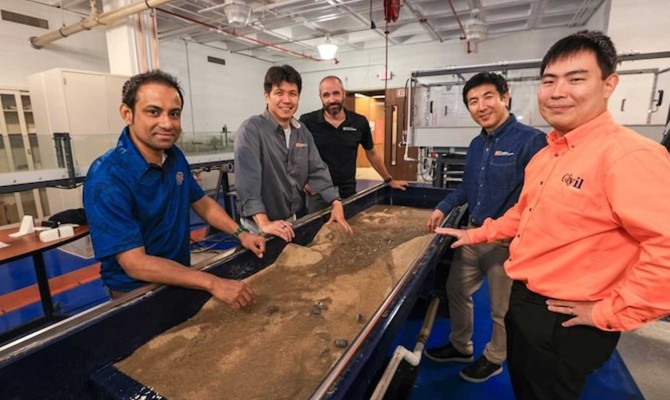 Engineering researchers stand next to a stream table in UTEP’s Hydrology Lab.